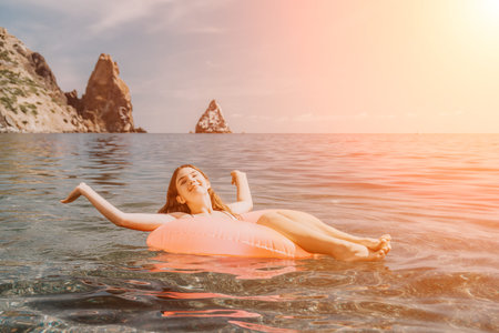 Woman swimming vacation floating on a pink inflatable ring in clear sea water during a sunny day at...