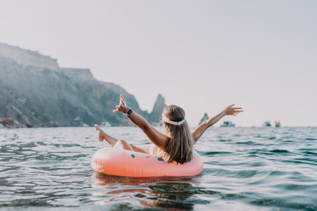 Woman, sea, floating. Happy woman enjoying summer vacation on a pink inflatable ring with coastal...