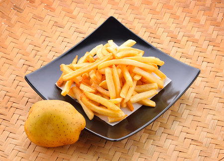 Fries fry in a basket on a wooden background