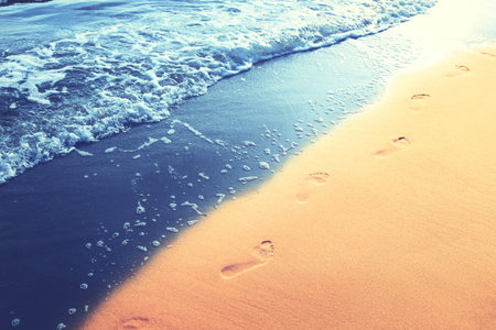 Detail of human feet in the golden sand at the beach. Summer travel and vacation concept.