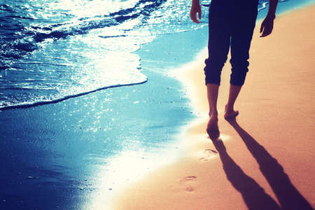 Detail of human feet in the golden sand at the beach. Summer travel and vacation concept.の写真素材