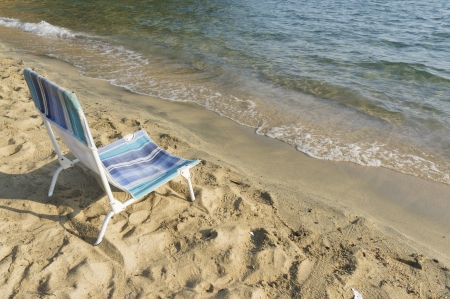 White beach chair, with blue-stripes material, near by the seashoreの写真素材