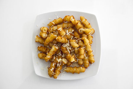 French fries on a white plate on white background under studio lights