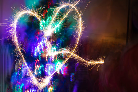 Heart on a bright background from sparklers. The photo was taken with a slow shutter speed, and...