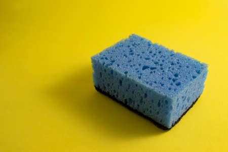 Colored Blue Kitchen Dishwashing Sponge on a Yellow Background. Home Cleaning Items.の写真素材