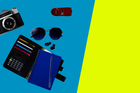 Retro Camera with Travel Accessories and Items on Blue and Yellow Backgrounds with Copy Space....