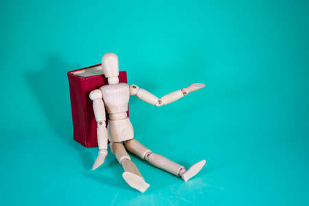 Wood Man and Book. Wooden Figure Sitting. Cheerful Wooden Doll on a Blue Background with a Book. Reading Books Shows Learning. education concept.の写真素材