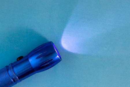 Blue Background with Flashlight On. Turned on Flashlight on a Blue Background. Light Illuminates the Way, Exit from Difficult Situations. Turned on the Flashlight on a Bright Background.の写真素材