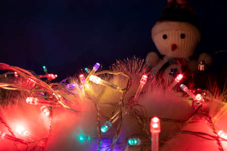 Colorful Christmas Lights on a Blue Background. Christmas and New Year Decorations. Garland Close-up with Luminous Lanterns on the Background of a Snowman. Happy New Year and Merry Christmas.の写真素材