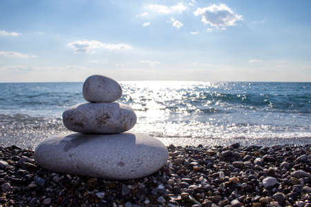 Pyramid stones balance on the sand of the beach. Object on the background of the sea. Calm concept.の写真素材