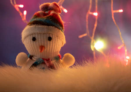 Christmas Decor Close-up with Glowing Pink, Yellow, Orange Lanterns on the Background of a Snowman. Colorful Christmas Lights on a Blue Background. Christmas and New Year Decorations. Happy New Year and Merry Christmas.の写真素材