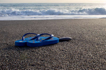Sunny tropical beach with turquoise water, Calabria, Italy vacation, hot summer day. Close up of flip flops on beach. Holiday concept.の写真素材