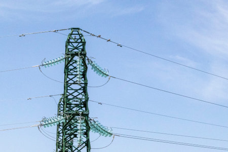 Metal electric towers under a blue sky. High-voltage lines and power poles on a sunny day with...