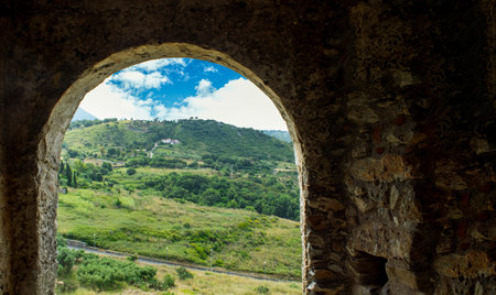 Window of a Stone Battle Tower Overlooking the Coast with Green Hills of Trees in Calabria, Italy.の写真素材