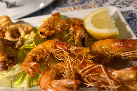 Grilled shrimp with lemon, garlic and white sauce on a plate at an Italian restaurant. Seafood.