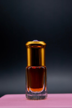 Bottle of perfume or oil on a dark background. Mockup of a perfume bottle standing on a pink...
