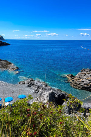 This scenic coastal setting showcases bright blue water against rocky shores under a clear sky....