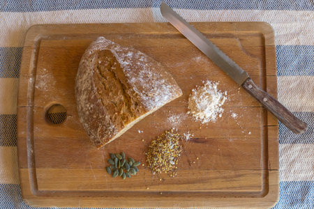 Wooden tray with bread, seeds, flour and a bread knife