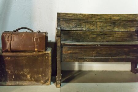Old leather cases and an empty wooden benchの写真素材