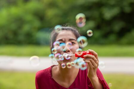 Portrait of beautiful young asian woman with Carmen red dress blowing bubble in the parkの写真素材