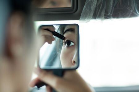 Beautiful young asian woman painting eyeshadow on eye lid in her carの写真素材