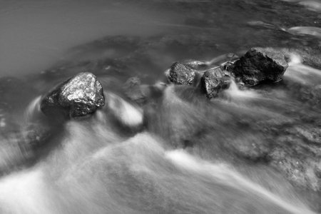 Abstract of Rocks in stream with smooth flowing water with long exposure techniqueの写真素材