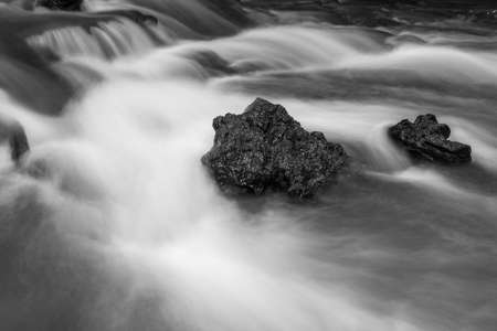 Black and white abstract of Rocks in stream with smooth flowing water with long exposure techniqueの写真素材