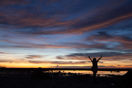 Silhouette of the woman raise her hand in the evening at Pakarang beach, Phang Nga, Thailandの写真素材