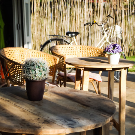 Wooden table seats peace , chairs , flower vase, bicycle and cactus in coffee cafeの写真素材