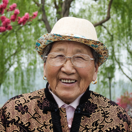 HANGZHOU, CHINA - April 13, 2011 : View in the mist of Xihu, the west lake in hangzhou china, this is image of  old woman wearing a hat and glasses, smiling brightly.のeditorial素材