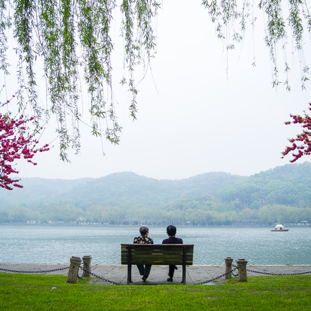 HANGZHOU, CHINA - April 13, 2011 : View in the mist of Xihu, the west lake in hangzhou china, this is image of two Chinese old women sit on the bench by the lakeのeditorial素材