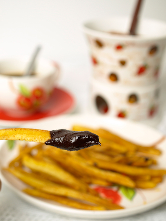 Homemade potatoes chips with chocolate fondue on white backgroundの写真素材