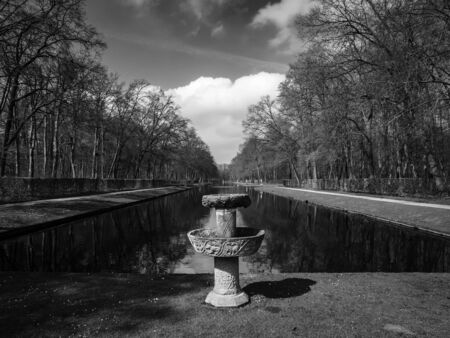 Black and white image of stone fountain by the beautiful pond in the park of Kasteel De Haarの写真素材