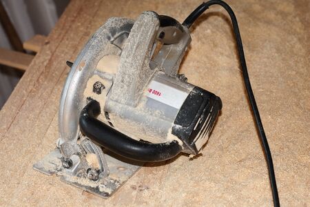 Electric circular saw over wood with sawdustの写真素材