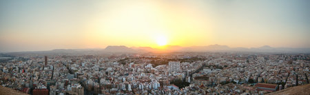 Panoramic view of the old town of Alicante, backlit at sunset from the top of the castle of Santa...