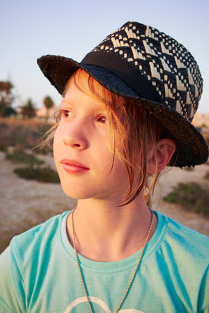 Portrait of girl with golden hair close-up in a black hat. A girl admires the sunset. Las salinas,...