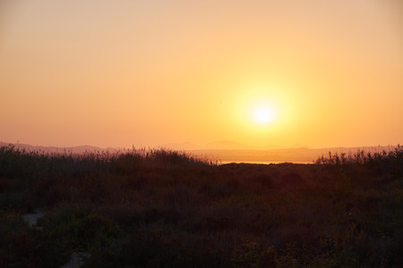 View of the salt lake with a beautiful pink water. Sunset orange sun, the neighborhood.Las salinas, Torrevieja, Spainの写真素材