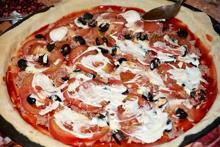 Cooking delicious pizza with tomatoes, olives, mayonnaise and meat.の写真素材