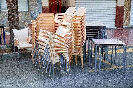A pile of stacked chairs in front of a street cafe.の写真素材