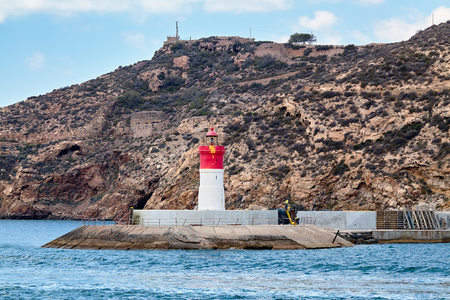 Red and white lighthouse near the fort of Christmas and the seaport. Cartagena, Spain.の写真素材
