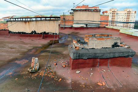 A view of the elements of the roof of a modern multi-storey brick building. Ventilation, the door to the attic, the tower elevator shaft. Wires, cables, waterproofing and drainage. St. Petersburgの写真素材