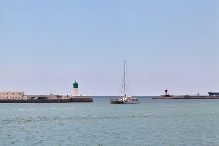 A pleasure boat sails on the Mediterranean Sea between two lighthouses. Cartagena, Spain.の写真素材