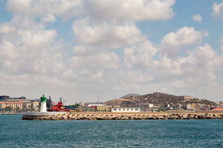 Cartagena, Spain - July 13, 2016: Green and white lighthouse, long breakwater at the entrance to the port.のeditorial素材