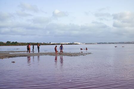 Torrevieja, Spain - June 26, 2016: Different people, men, women and children are taking procedures on a salt lake with pink water. At lake Las Salinas.のeditorial素材