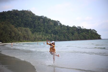 A woman kicking water splashes on the beachの写真素材