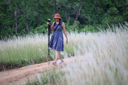 A female photographer taking pictures in grass color white, Thailand