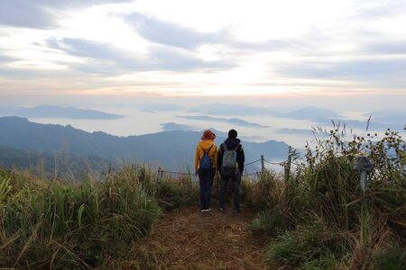 Man and woman standing in the fog and mountain view at Phu Chi Fa National Park, Chiang Rai, Thailandの写真素材