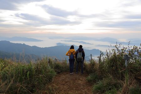 Man and woman standing in the fog and mountain view at Phu Chi Fa National Park, Chiang Rai, Thailandの写真素材