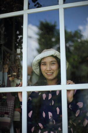 A woman smiling through a glass windowの写真素材