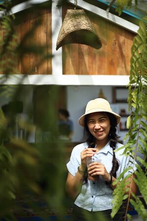 Woman holding a drink and standing in the gardenの写真素材